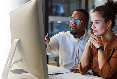Photo: two people looking at computer screen learning web basics like HTML, CSS, Javascript by attending ONLC Training Centers classes.